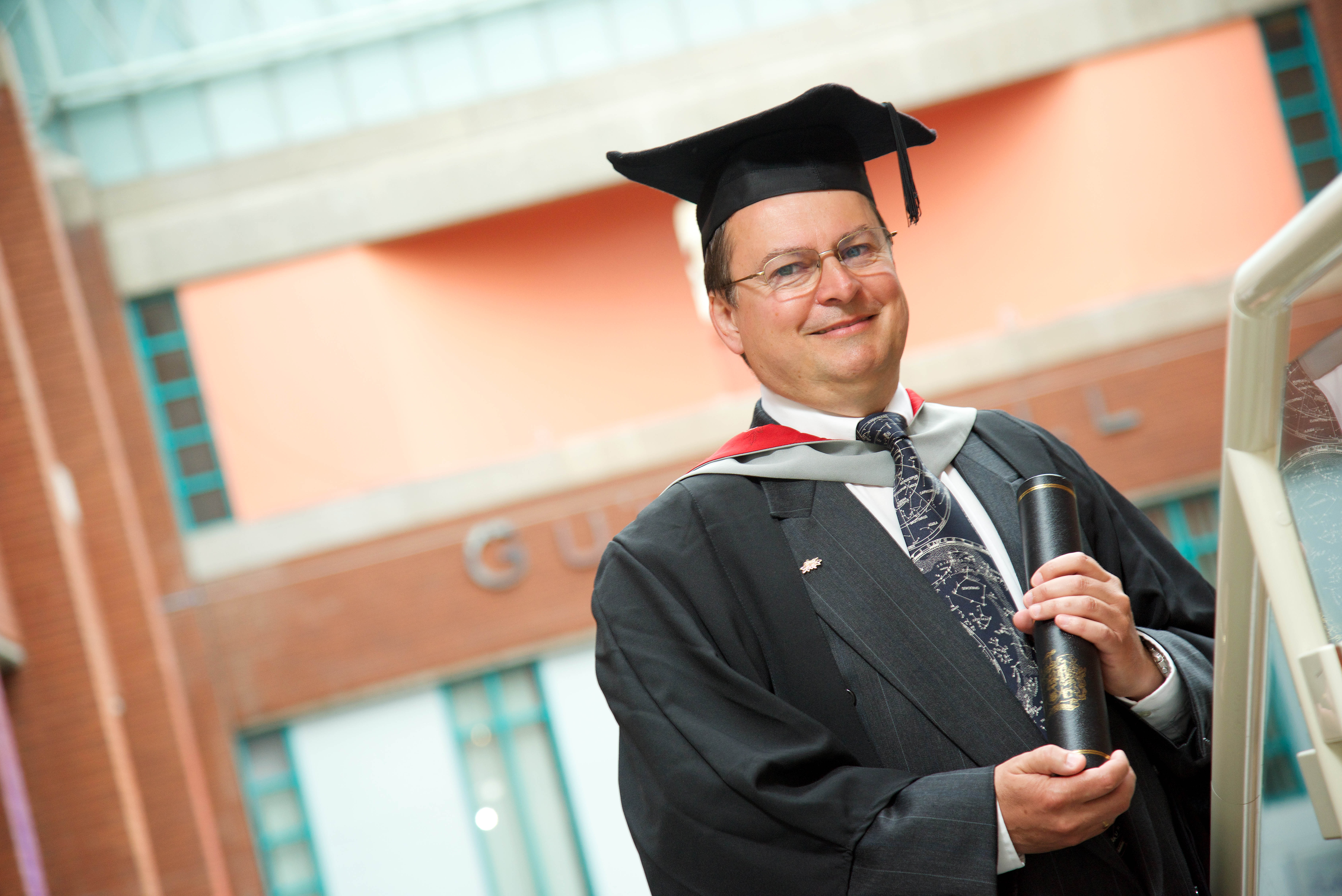 Person in graduation cap and gown smiling