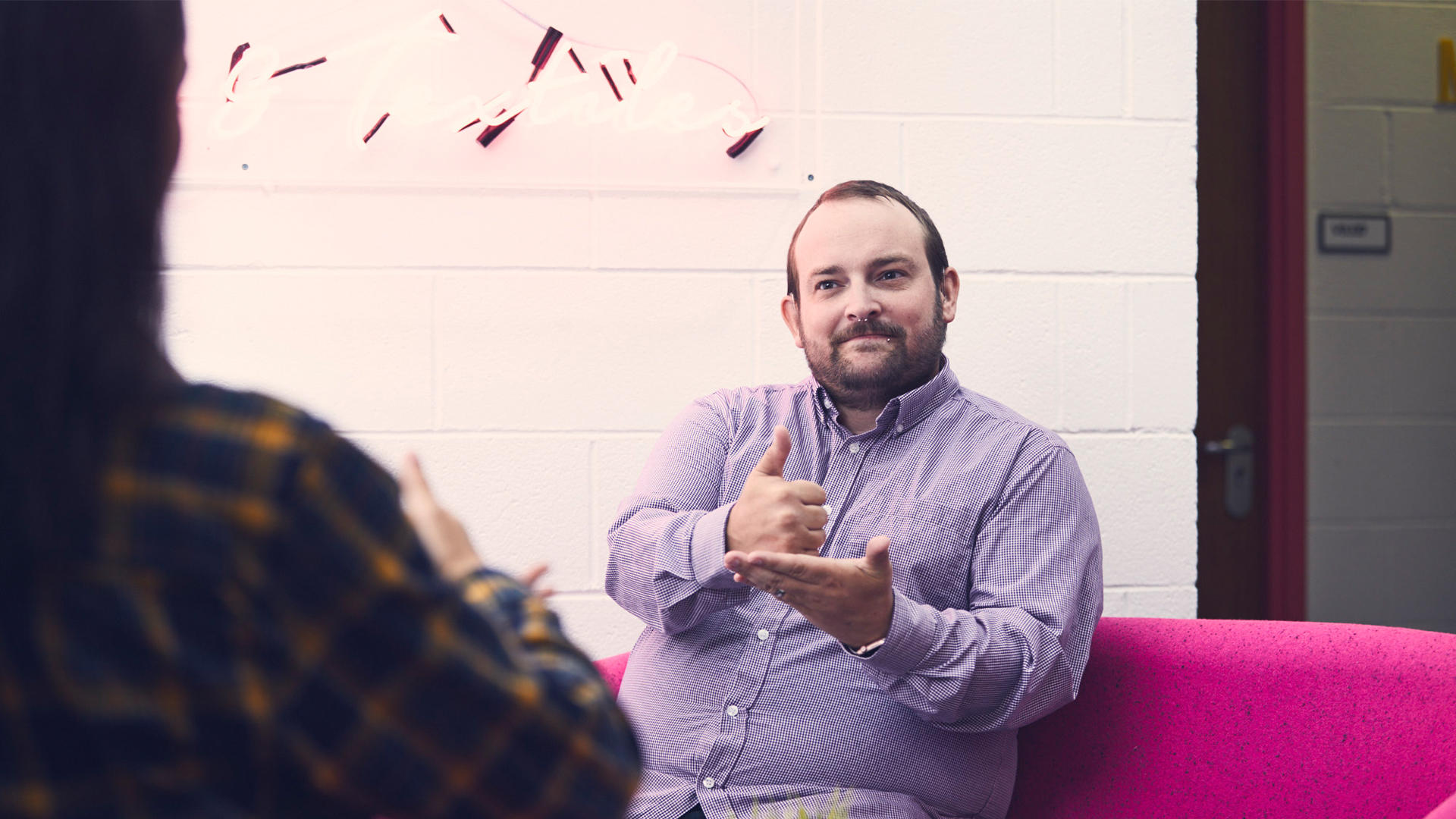 Students using sign language sat in a social space