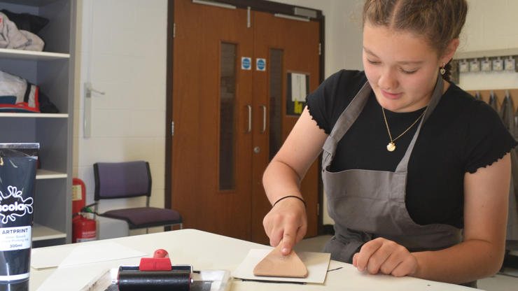 A student makes a relief print using lino cutting techniques.