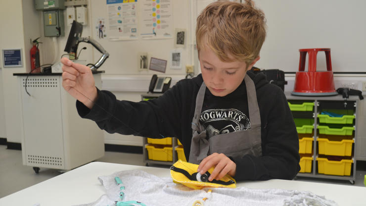 A young student uses felt appliqué to decorate a bag.