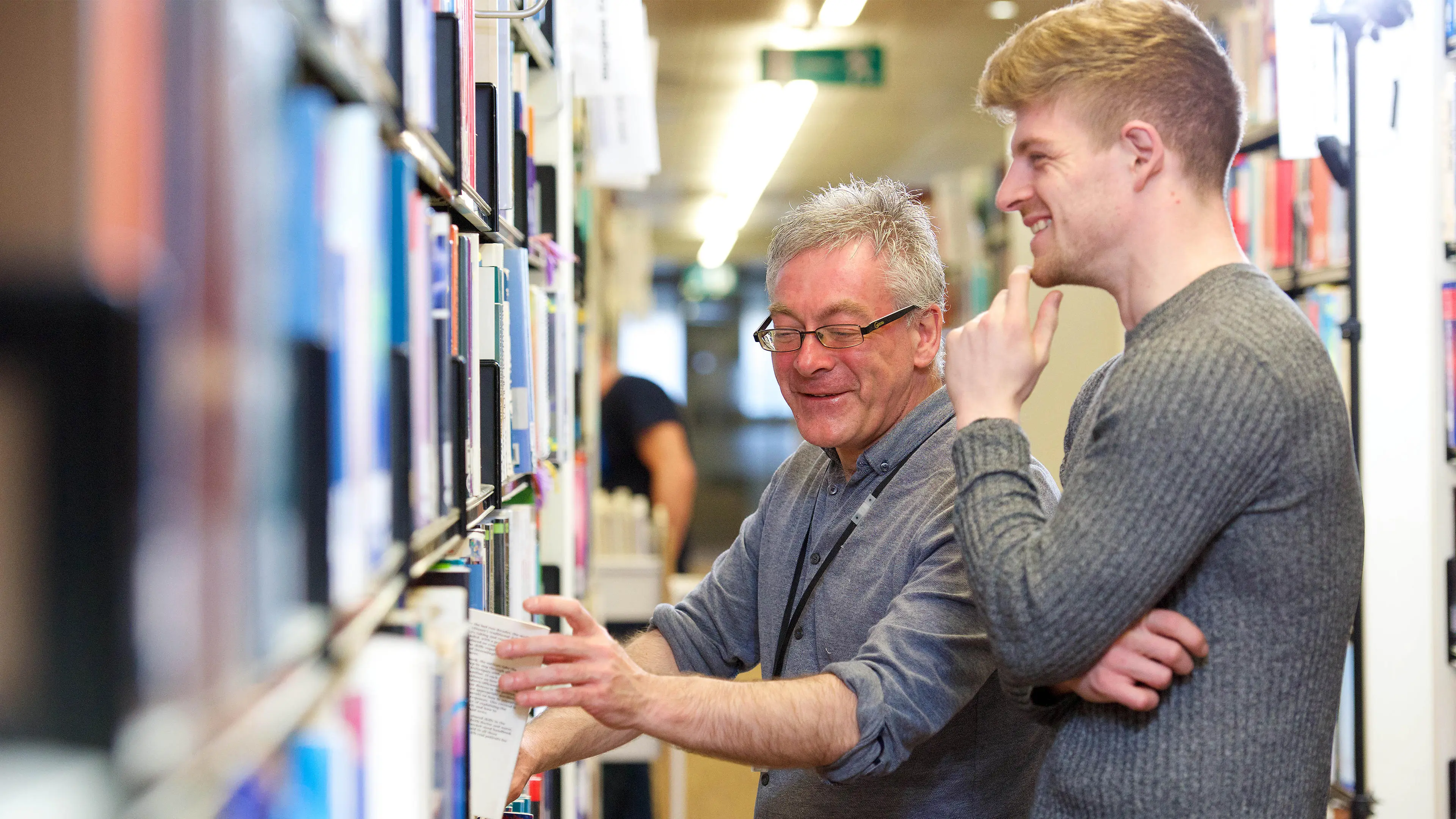 Staff member helping student in the library