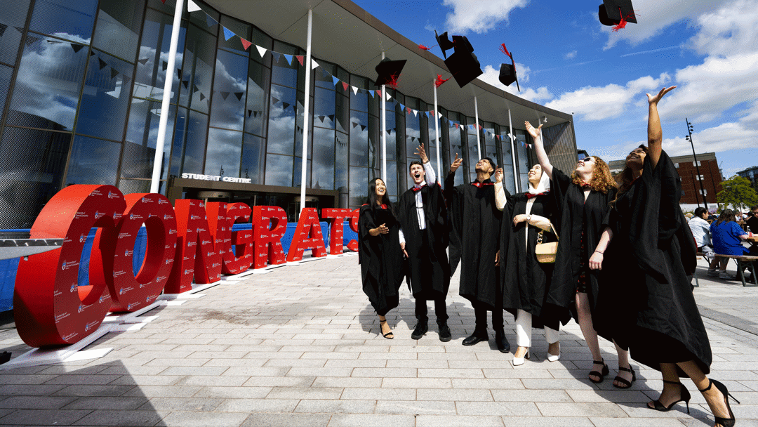 graduates throwing their caps outside the student centre