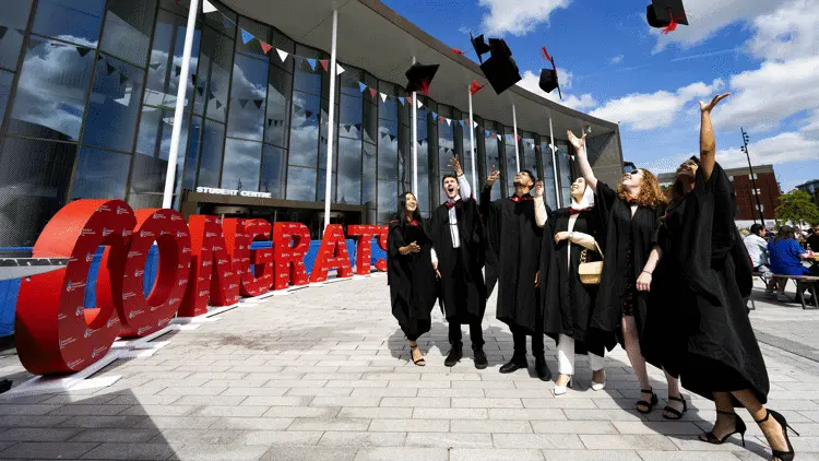 graduates throwing their caps outside the student centre