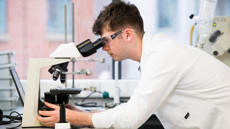 medical sciences mres student looking through a microscope