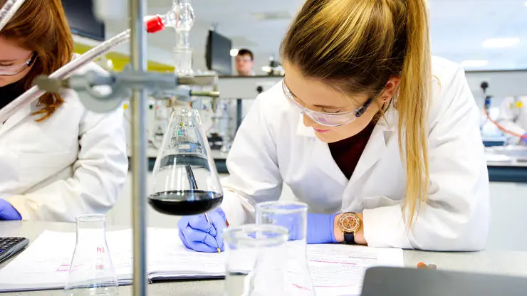 Students taking notes of an experiment in a chemistry lab
