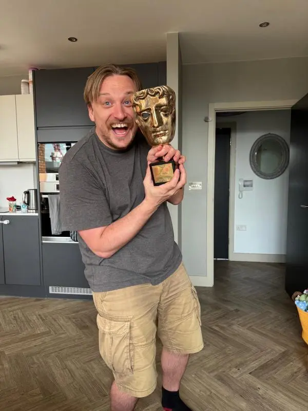Alumni Dom Hodge holding a BAFTA