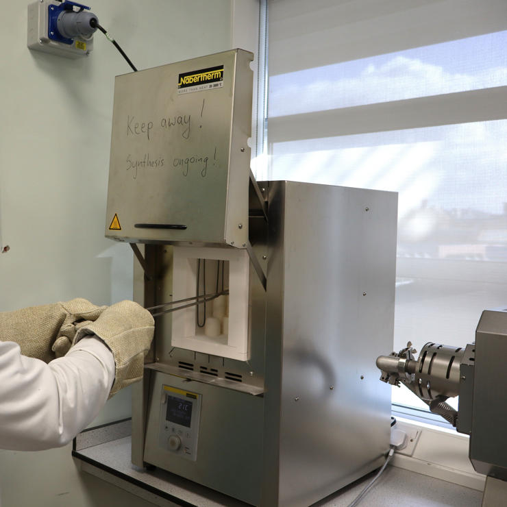 Student removing an ampoule from a box furnace in the Synthetic Quantum Materials Laboratories