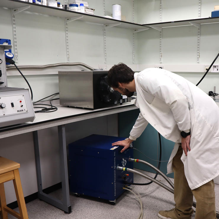 Student turning on a compressor of a dry cryostat to start a low-temperature experiment in the Synthetic Quantum Materials Laboratories