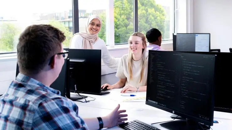 Two students pair programming with specialised hardware for software development.