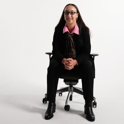 Zuleikha Chikh sat on chair in suit.