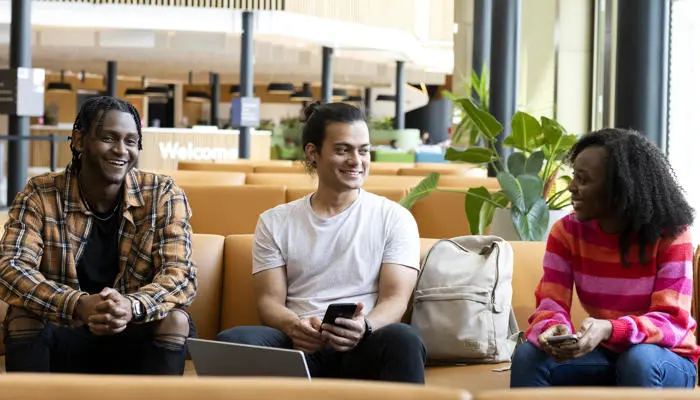 three students in the student centre sat on a sofa