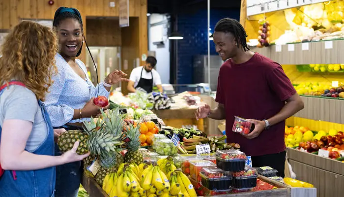 three students looking at fruit in preston market