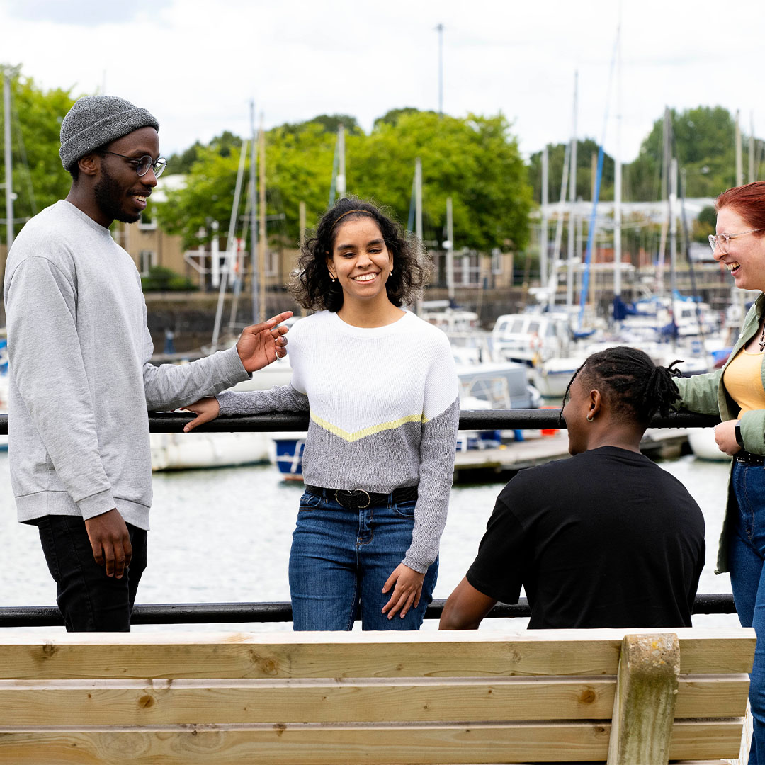 Students chatting by a bench at Preston marina