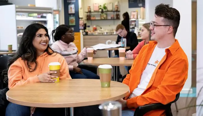 Students sitting at a table drinking coffee in Greenbank Building