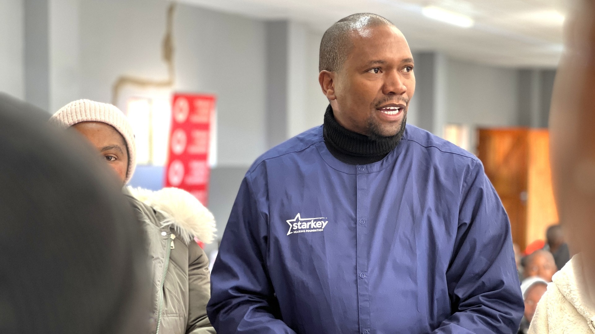 Khotso Kebise working with the Starkey Hearing Foundation in a medical uniform.