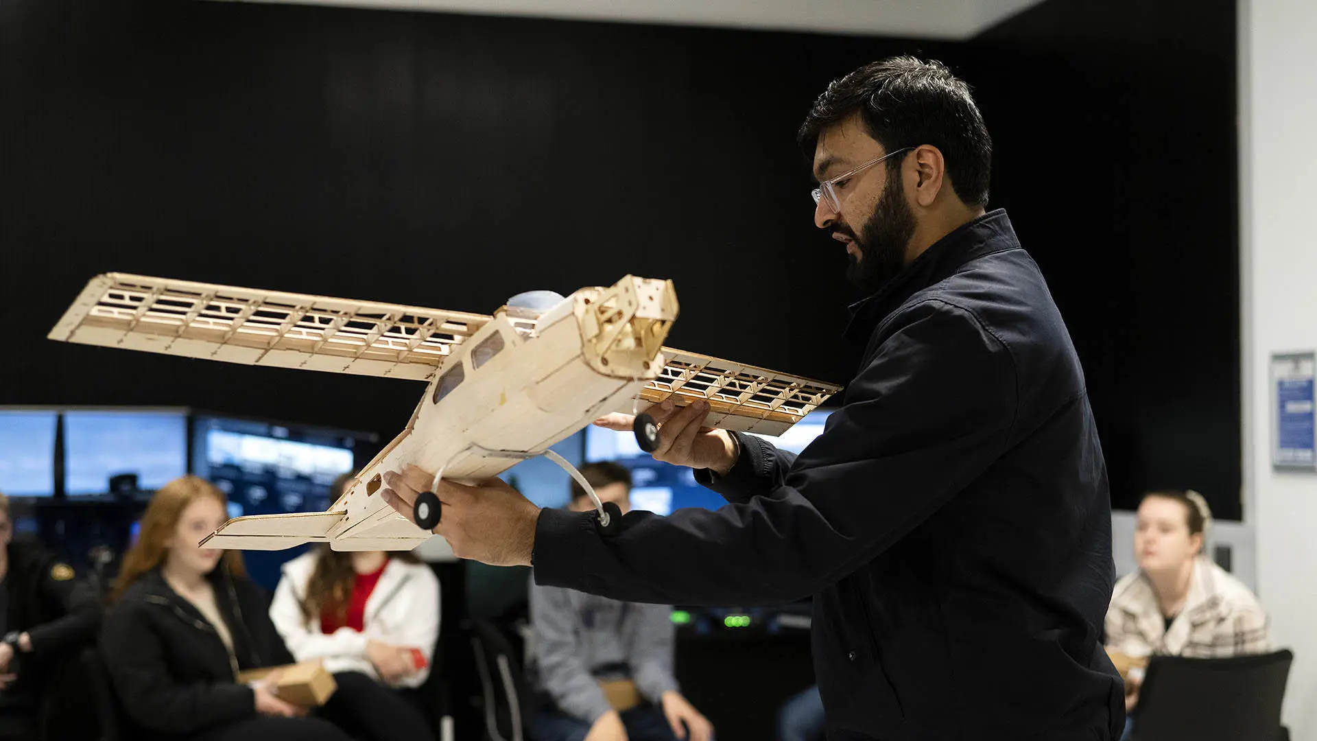 A lecturer demonstrates aerospace engineering with a model aeroplane