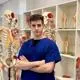 medical student poses next to a skeleton