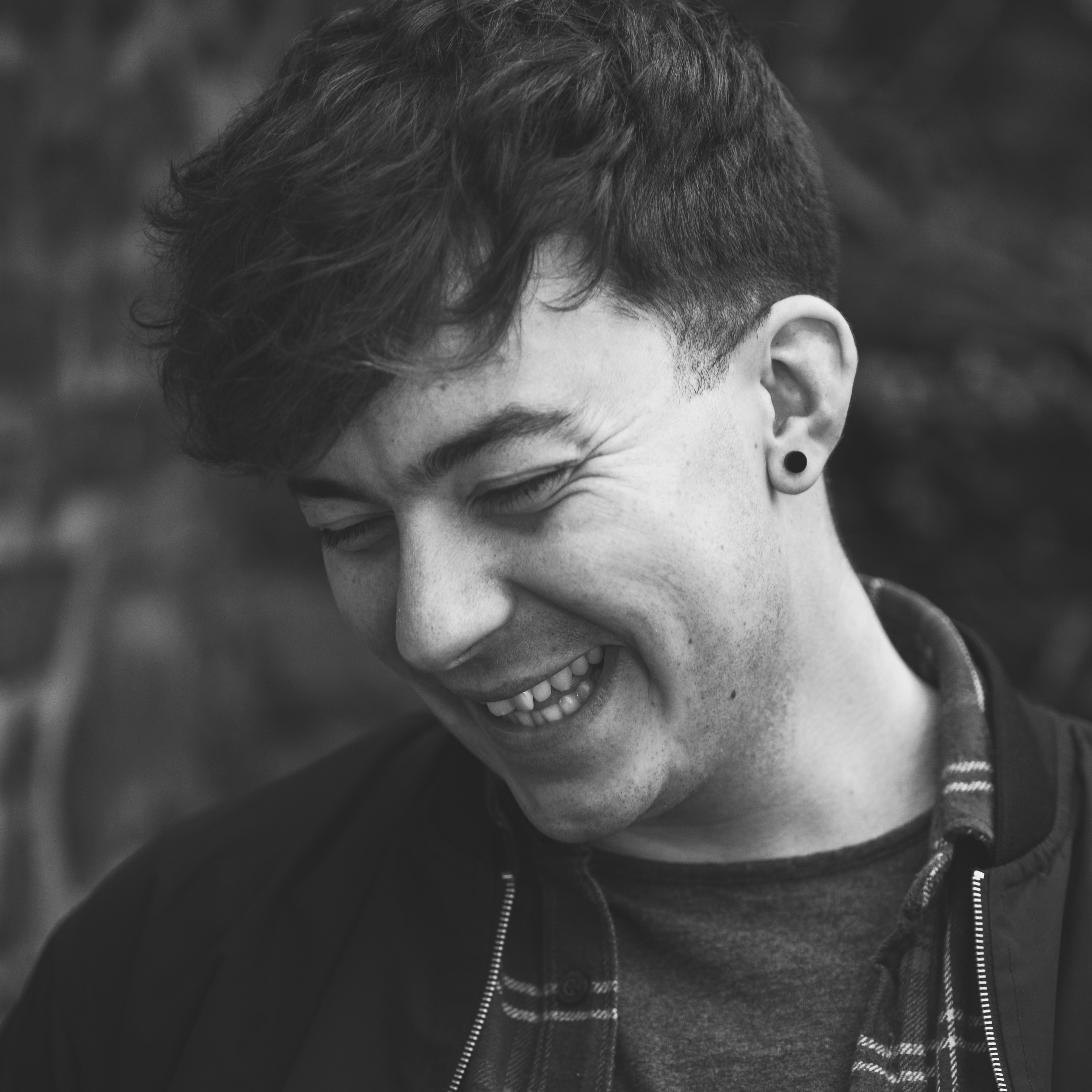Harry Jones in a shirt and jacket, smiling and looking away from camera