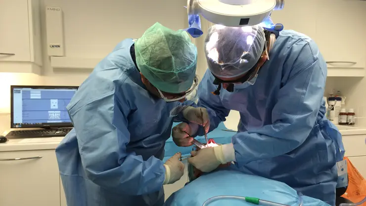 Dental surgical training session between a mentor and student, working on a patient