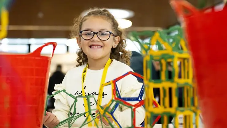 small child smiling at the camera and surrounded by scientific equipment at Lancashire Science Festival