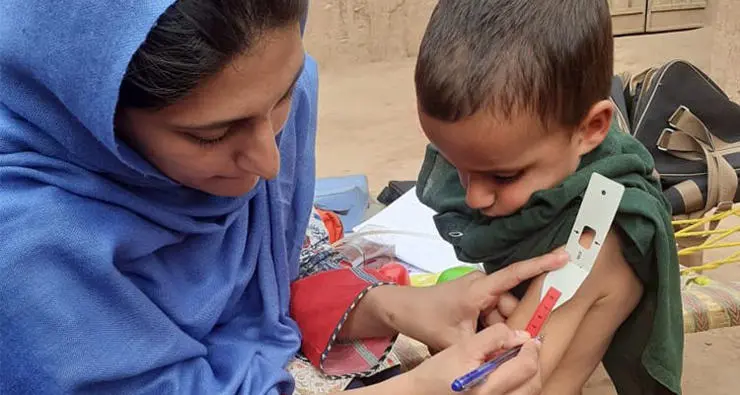 Research Assistant measuring a child’s mid upper arm circumference (MUAC).
