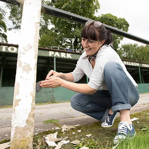 Student painting and tidying at Nelson Football Club.