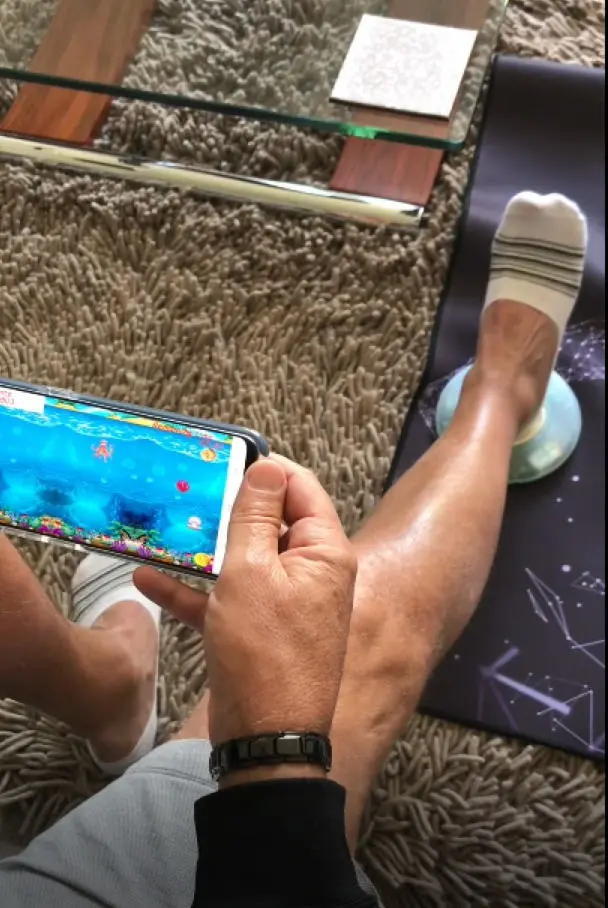 Mark Seed doing his knee bending exercises (knee flexion) using The Slider, following a total knee replacement. The Slider is communicating with a dedicated app on Mark’s mobile phone, which allows him to do a range of exercises. Each exercise also has specially designed games to encourage Mark to do the exercise. Mark can see how he is doing and the hospital is kept informed of his progress.