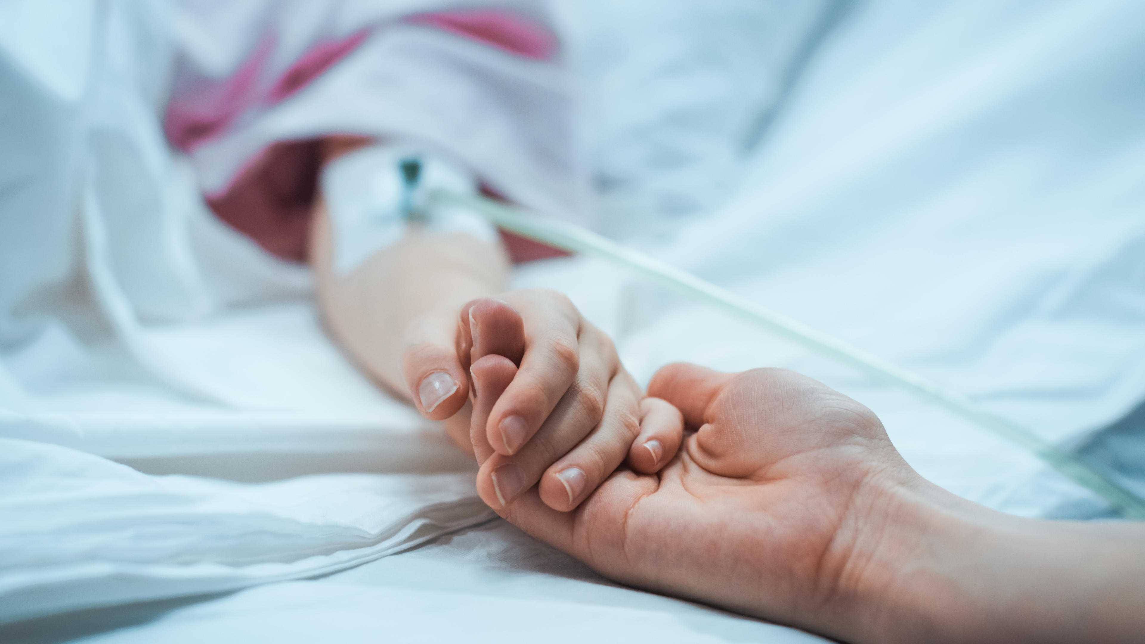 Woman's hand holding a child's hand in hospital. Adobe stock image.