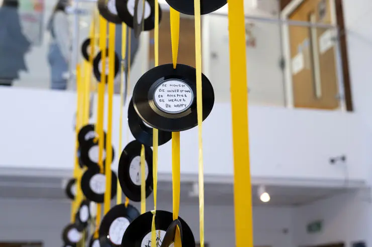 The exhibition featured vinyl records hanging from yellow ribbon