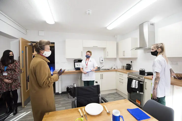 HRH the Princess Royal visiting the kitchen assessment demo area with students Rachel Lindsay and Clara Harvey-Hunt